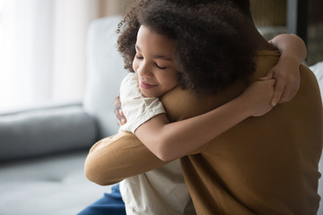 Happy cute African American daughter and father hugging, feeling love