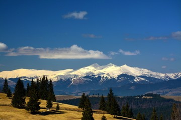 Spring landscape with mountain tops covered with snow