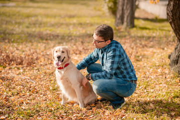 Portrait of young man sitting hugging with golden retriever dog. Friendship, pet and human. Man playing with dog