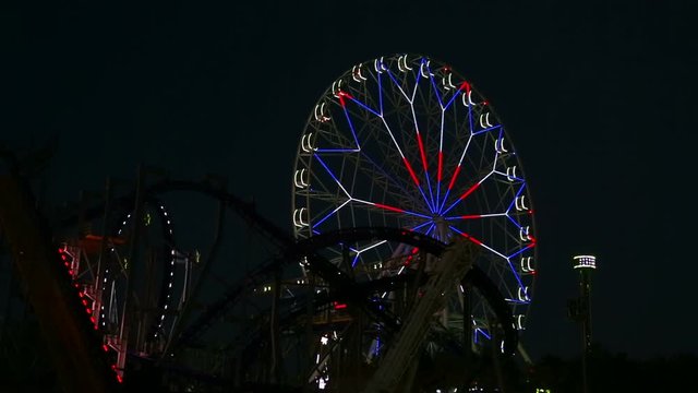 Glowing lights amusement rides in an amusement park in the evening