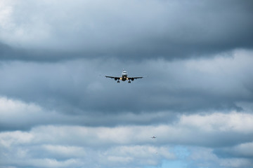 Fototapeta na wymiar Airplane in landing approach with dark cloudscape