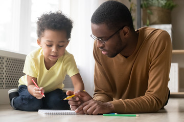 African American father and toddler son drawing colorful pencils together