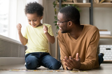 Smiling African American father and toddler son playing puzzle