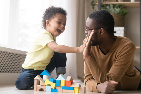 African American father with toddler son playing with wooden constructor