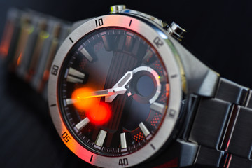 Luxury watch under colored light, close-up, black background