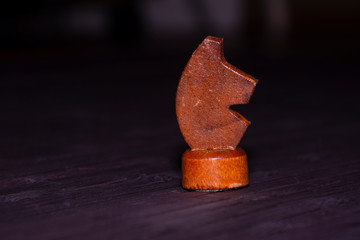 Figure of a black knight in a game of chess. Close-up photo. Black wood background.