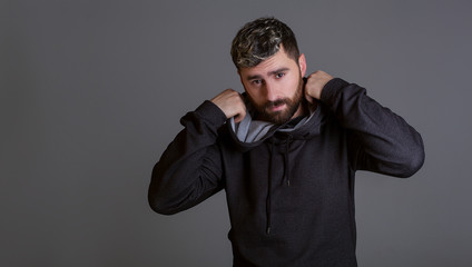 Fototapeta premium Stylish man on a gray background. Model tests of a man in a tracksuit. Men's hairstyle
