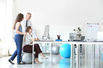 Young business people sitting on fitballs while working in office