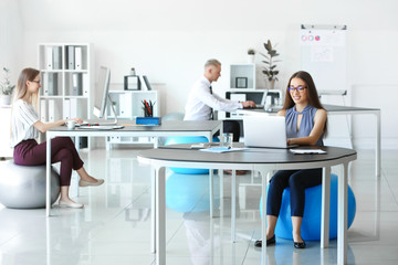 Young business people sitting on fitballs while working in office