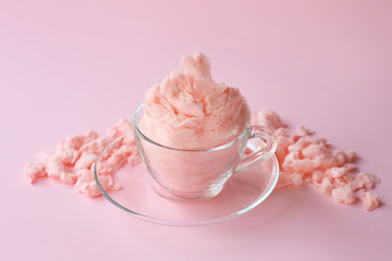 Glass cup with tasty cotton candy on color background