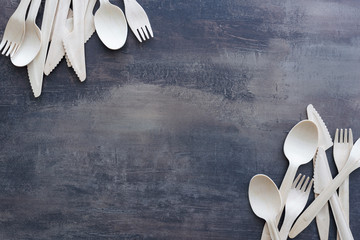 Top view of scattered wooden cutlery - spoons, forks and knifes on marble black kitchen counter....