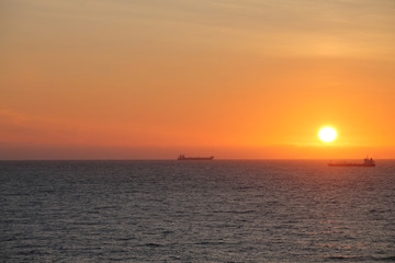 Seat at sunset with ships at the horizon 