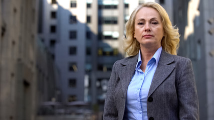 Professional female lawyer in formal suit looking camera outdoors, experience