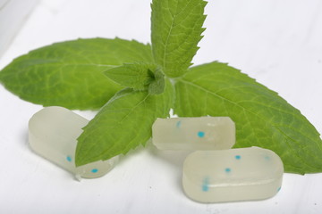 Peppermint candies for breath freshening. With refreshing microgranules. Cooling menthol for sore throat. Nearby mint leaves.