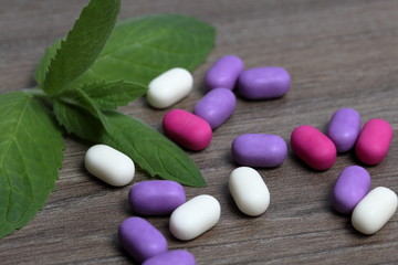 Dragee for refreshment of breath. Different color. Nearby mint leaves.