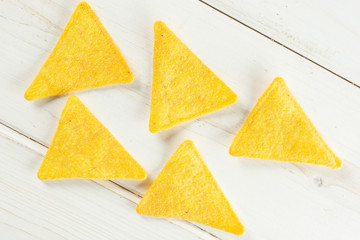 Group of five whole cheese tortilla chips flatlay on white wood