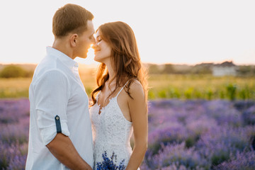 Sensual Couple in Lavender Field Romantic Time. Beautiful Young People Hug, Kiss Outdoor Medium Shot. Attractive Woman Hold Bouquet. Caucasian Man and Girl Embrace on Purple Flower Meadow