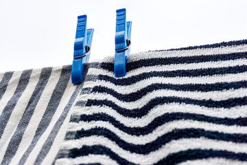 Dishcloths drying on clothesline. Closeup of two horizontal and vertical striped grey black white towels drying on a line with two large blue clothespins against a grey cloudy sky. 