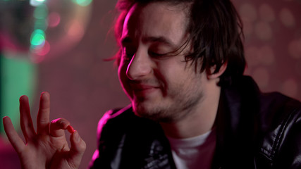 Male clubber holding ecstasy pill, addiction to recreational drugs, intoxication