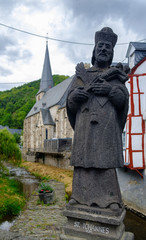 The picturesque village of Monreal with John of Pomuk Statue at the stone bridge in Eifel region,...