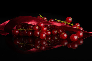 Lot of whole fresh red currant with red ribbon isolated on black glass