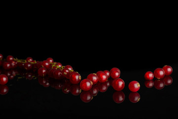 Lot of whole fresh red currant in row isolated on black glass