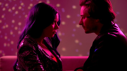Young couple looking seductively at each other in night club, passion and flirt