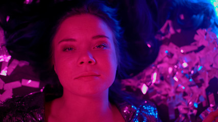 Careless female clubber lying on floor among confetti, wasting life concept