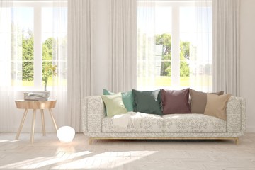 Fototapeta premium Stylish room in white color with sofa and summer landscape in window. Scandinavian interior design. 3D illustration