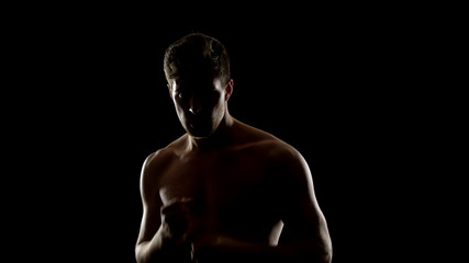 Fototapeta na wymiar Topless free fighter preparing for sparing, dark background, shadow fight