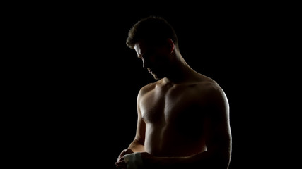 Boxer putting on straps preparing for combat on a dark background, kickboxing