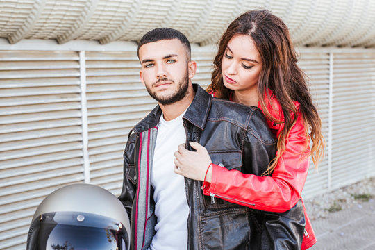 Portrait of couple with motorcycle helmet wearing leather jackets