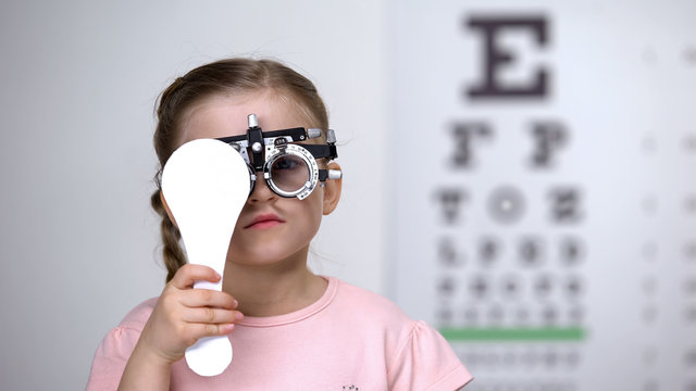 Child in special glasses with eye closed checking vision, astigmatism diagnosis
