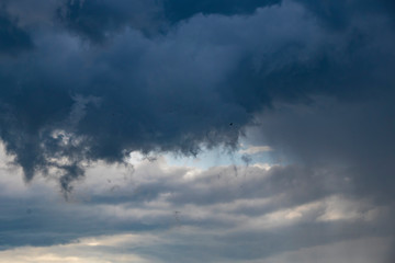 Dark thunder clouds on the blue sky. Abstract background with clouds on blue sky.
