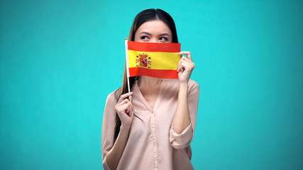 Girl covering face with Spanish flag, learning language, education and travel