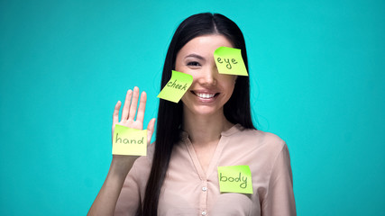 Female student covered with English body parts sticky notes, learning language