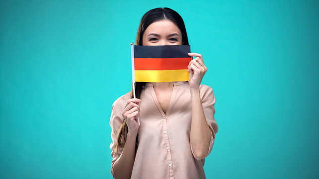 Lady covering face with German flag, learning language, education and travel