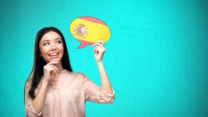 Curious woman holding Spanish flag sign, learning language, education abroad