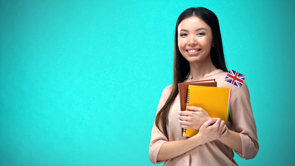 Cheerful woman holding British flag book, education abroad, learning language