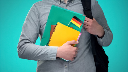 Male student holding notebooks with German flag, international education program
