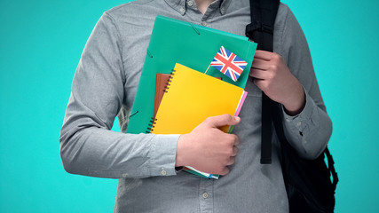 Student holding notebooks with British flag, international educational program