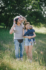 Happy family posing in a green park on sunny day.