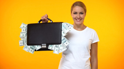 Caucasian female showing briefcase full of dollars, stock market investment