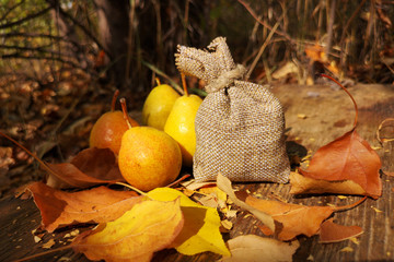 Yellow pear and a bag on a wooden table on a background autumn bokeh. The background of yellow leaves. The concept of the autumn winter supplies, the harvest garden