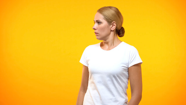 Scared young lady looking left on bright background, frightened person, phobia