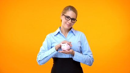 Female bank manager holding piggybank in hand, pension fund, deposit insurance