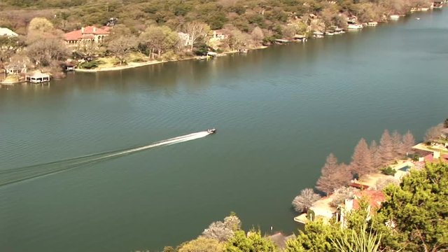 Speed Boat On Lake Travis In Austin Texas With Affluent Neighborhoods Lining The Banks.