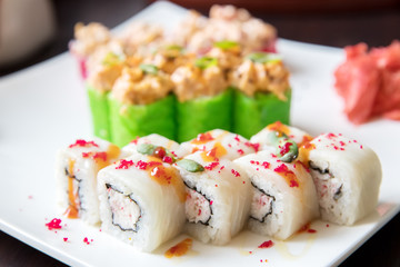 Fish rolls with perch and stuffing on a white square plate in the restaurant.