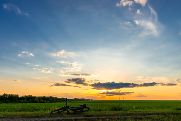 Bicycle lies on the ground, beautiful bright sunset