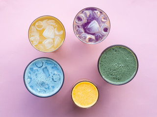 Glasses with colorful summer drinks, cocktails, vegetable strips, coffee drinks and orange juice, top photo, pink background. Concept for restaurant or bar